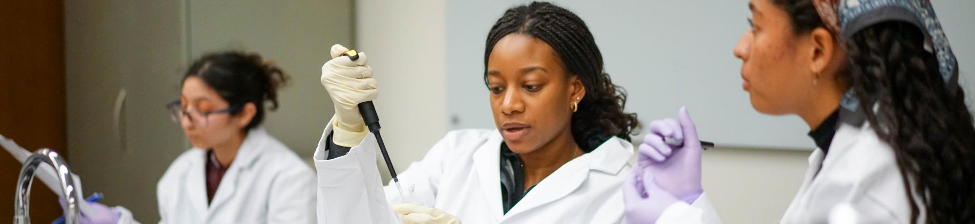  Students in white lab coats doing research