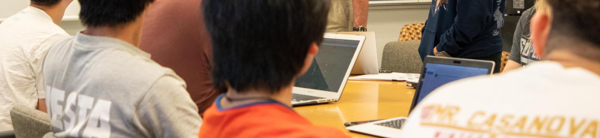 Instructor pointing at projected slides in a classroom of students