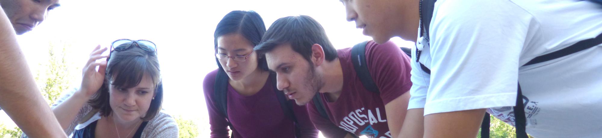 Students gathered outside observing a rock